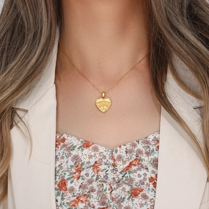 Detail of gold heart pendant necklace featuring evil eye design on a female model