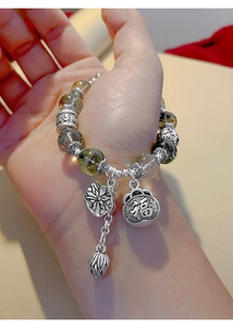 Close-up of Green Phantom Crystal bracelet with silver lucky bag and lotus pendants