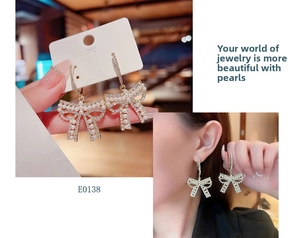 Macro detail of bow-shaped tassel earrings with pearls and S925 silver needles
