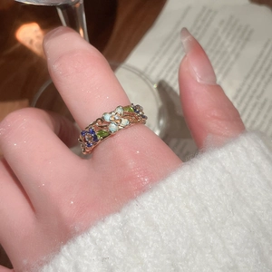 Detail of a gold-plated flower ring with blue enamel petals and zircon center on model