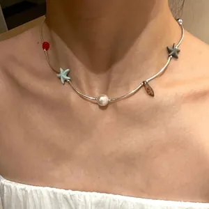 Colorful shell bead necklace with starfish charms and white pearl on model's neck
