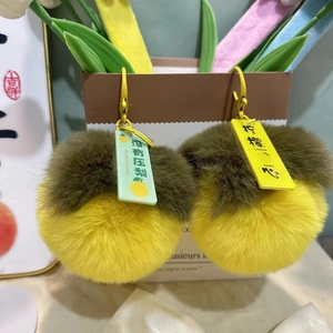 Dettaglio di portachiavi in peluche a forma di limone e pera con scritte divertenti