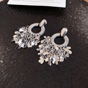 Detail of silver geometric fringe earrings with metal sequins on a dark tray
