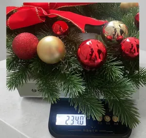 Detail view of a Christmas wreath with red bows and ornaments on a digital kitchen scale