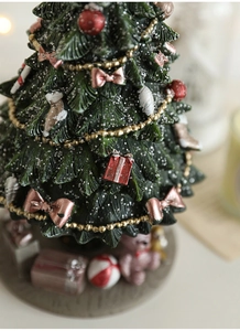 Detail of a green resin Christmas tree with pink bows, glitter, and colorful gift boxes
