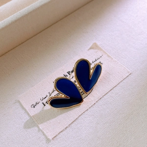 Macro view of blue enamel double heart earrings with gold trim on vintage card