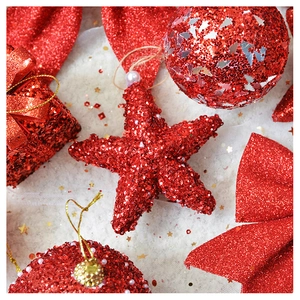 Detail of red glitter Christmas ornaments with star and bauble on white plush background