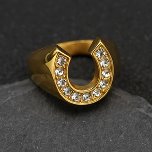 Gold stainless steel U-shaped horseshoe ring with white crystal inlay on stone surface