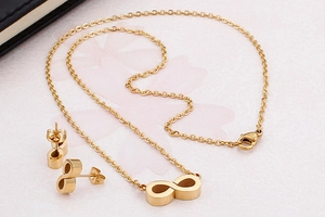 Detailed view of gold infinity symbol necklace and stud earrings set on pink background