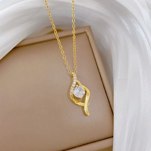 Detail view of gold-plated titanium necklace with teardrop pendant on brown jewelry box
