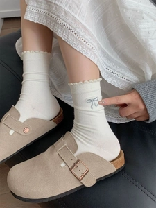 Detail von weißen Baumwollsocken mit blauer Schleifenstickerei und Rüschenbündchen