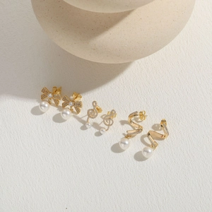 Elegant gold earrings set with pearls and zircons in bow, note and spiral designs