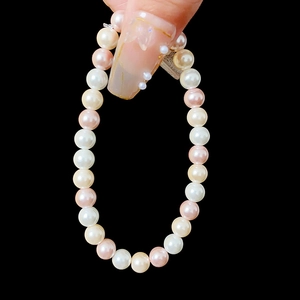 Detail of pink and white pearl necklace held vertically against a black background