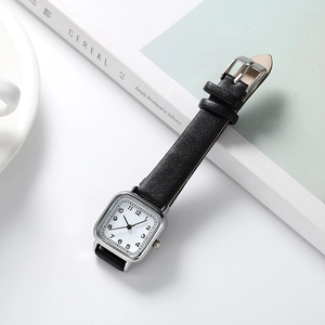 Détail d'une montre vintage carrée avec boîtier argenté et bracelet en cuir noir