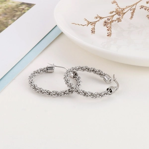 Vue macro des boucles d'oreilles créoles tressées en argent à texture détaillée