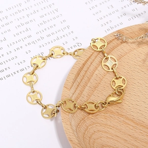 Unique stainless steel bracelet with golden coin-shaped links and lobster clasp on wooden tray