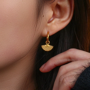 Close-up of a model wearing golden fan-shaped bohemian drop earrings in a stylish pose