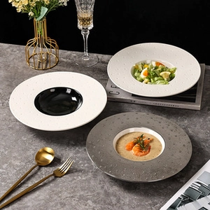 Close-up of three speckled ceramic plates in white, black, and grey on a stone table