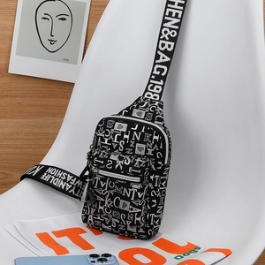Detail of a black nylon crossbody bag featuring white alphabet prints on a white chair