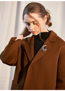 Elegant crystal moon brooch with large purple stone on brown wool coat collar