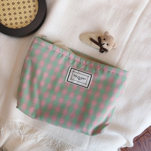 Pink and green plaid cotton makeup bag with Time to Party label on a cozy knit blanket