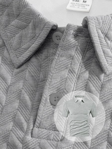 Vue détaillée du polo jacquard gris montrant la texture du tricot en chevrons de qualité