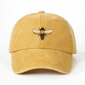 Detailed close-up of a mustard yellow washed cotton baseball cap with bee embroidery