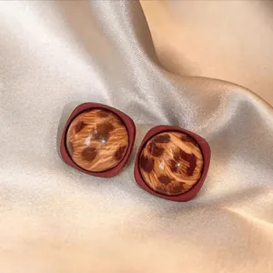 Vue macro de boucles d'oreilles vintage avec résine léopard dans un cadre carré rouge foncé