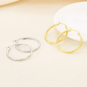 Detailed view of large gold and silver stainless steel hoop earrings on fabric background