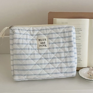 Beauty case trapuntato a righe blu mostrato in un ambiente domestico accogliente