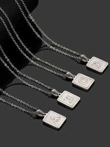 Macro shot of silver square letter pendants with mother of pearl inlay on black background