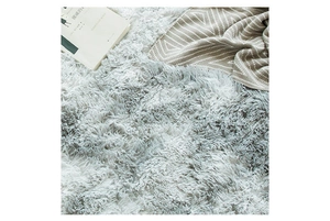 Close-up of soft gray shaggy rug texture with a book and striped knit blanket