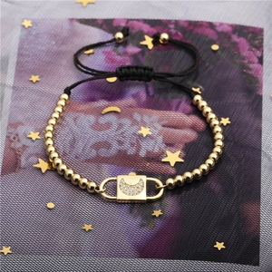 Close-up of zircon moon pendant on golden bead bracelet with adjustable black woven cord