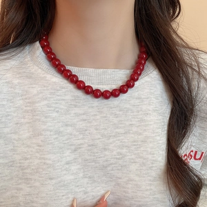 Close-up of minimalist red glass beaded necklace worn by a model on white shirt