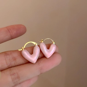 Macro di piccoli orecchini a cerchio con ciondoli a cuore rosa dall'effetto perlato