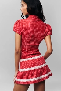 Rear view of a red polka dot top and white lace trim mini skirt set on a model
