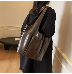 Detail of the side view showing the exterior pocket on a brown vintage PU leather tote bag