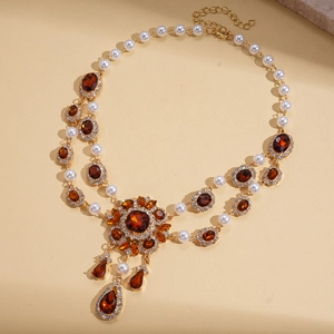 Detail of vintage gold necklace with amber crystal pendant and faux pearl accents