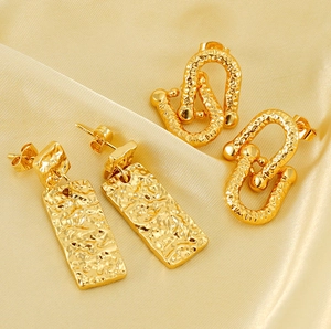 Detail of gold-plated earrings with hammered texture on elegant silk background