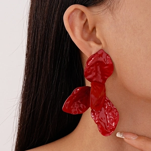 Model wearing large red wrinkled flower petal earrings with a glossy spray finish