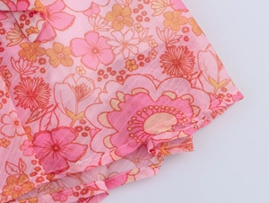 Dettaglio macro del tessuto in chiffon floreale rosa con cuciture e pizzi rifiniti