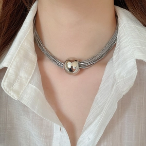 Detail of silver multi-layer chain necklace featuring a large metallic spherical pendant