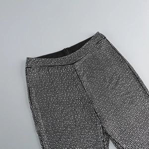 Vue détaillée d'un pantalon noir taille haute avec des ornements en strass argentés