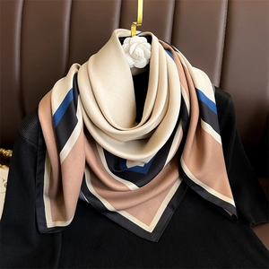 Élégant foulard en soie 90cm à motifs géométriques sur un pull noir avec broche camélia
