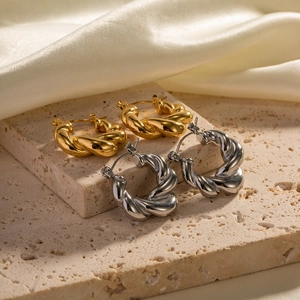 Macro shot of gold and silver croissant hoop earrings on natural stone and silk