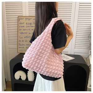 Detail shot of a soft pink ruched puff cloud shoulder bag styled in a chic interior setting