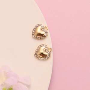 Detailed view of gold heart pendants with crystal rhinestones on a soft pink background