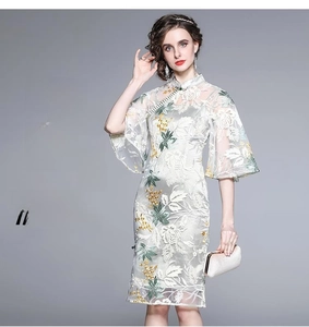 Detail of white lace cheongsam dress featuring green floral embroidery and mandarin collar