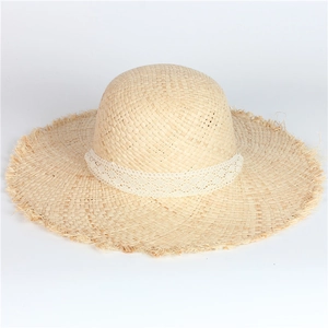Detailed close-up of handmade straw hat featuring white lace band and frayed edge detail