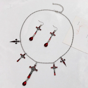 Gothic necklace set with silver cross pendants and teardrop red gemstones on white cloth